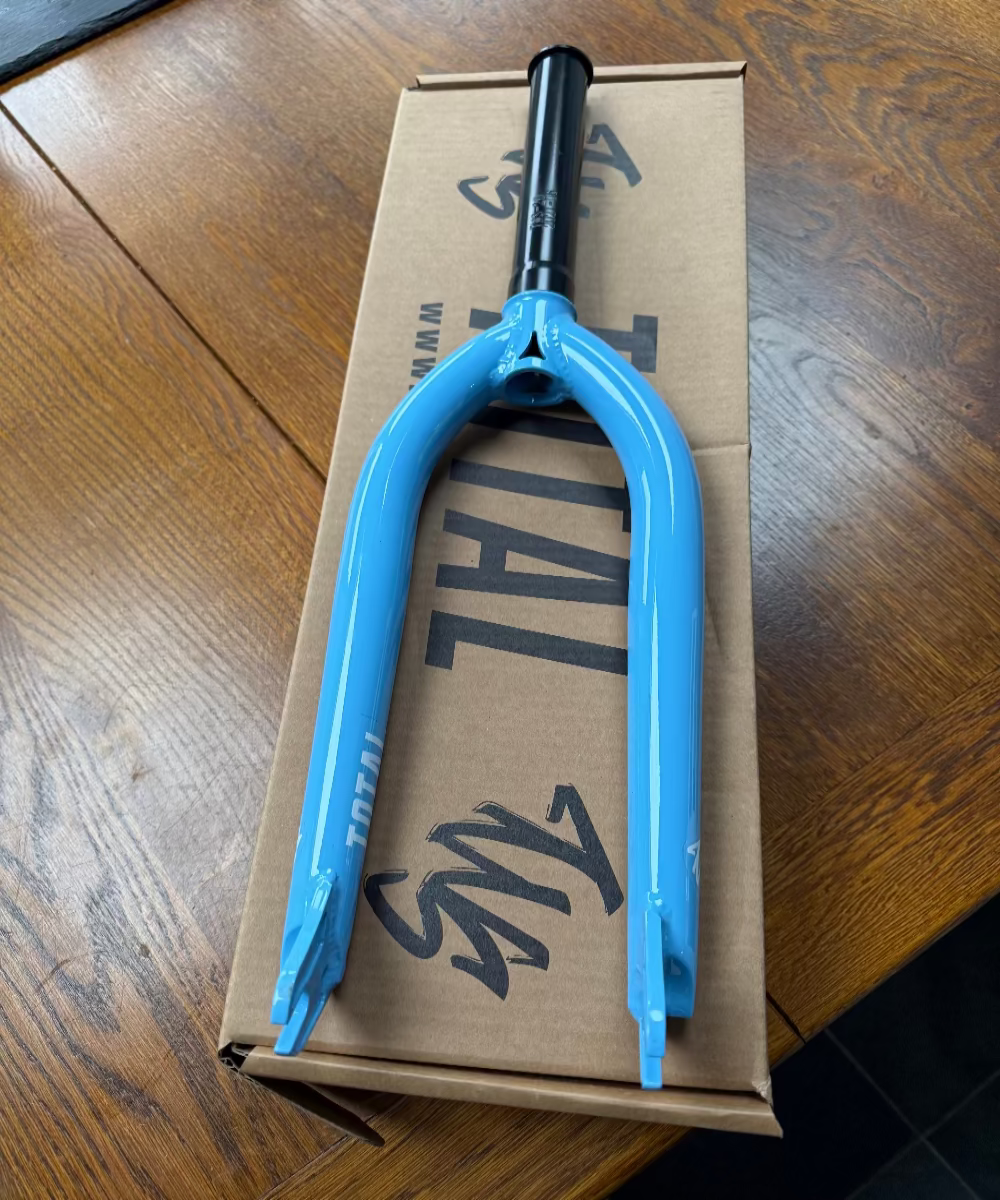Blue BMX fork on a cardboard box with visible branding on a wooden surface